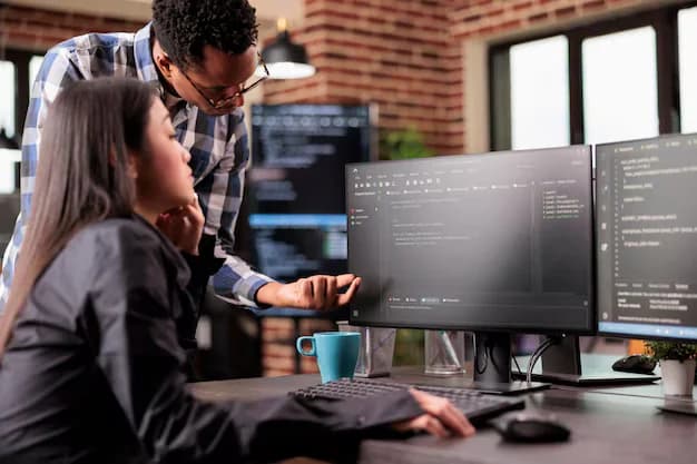 Software development team collaborating and reviewing code on computer monitors in a tech office
